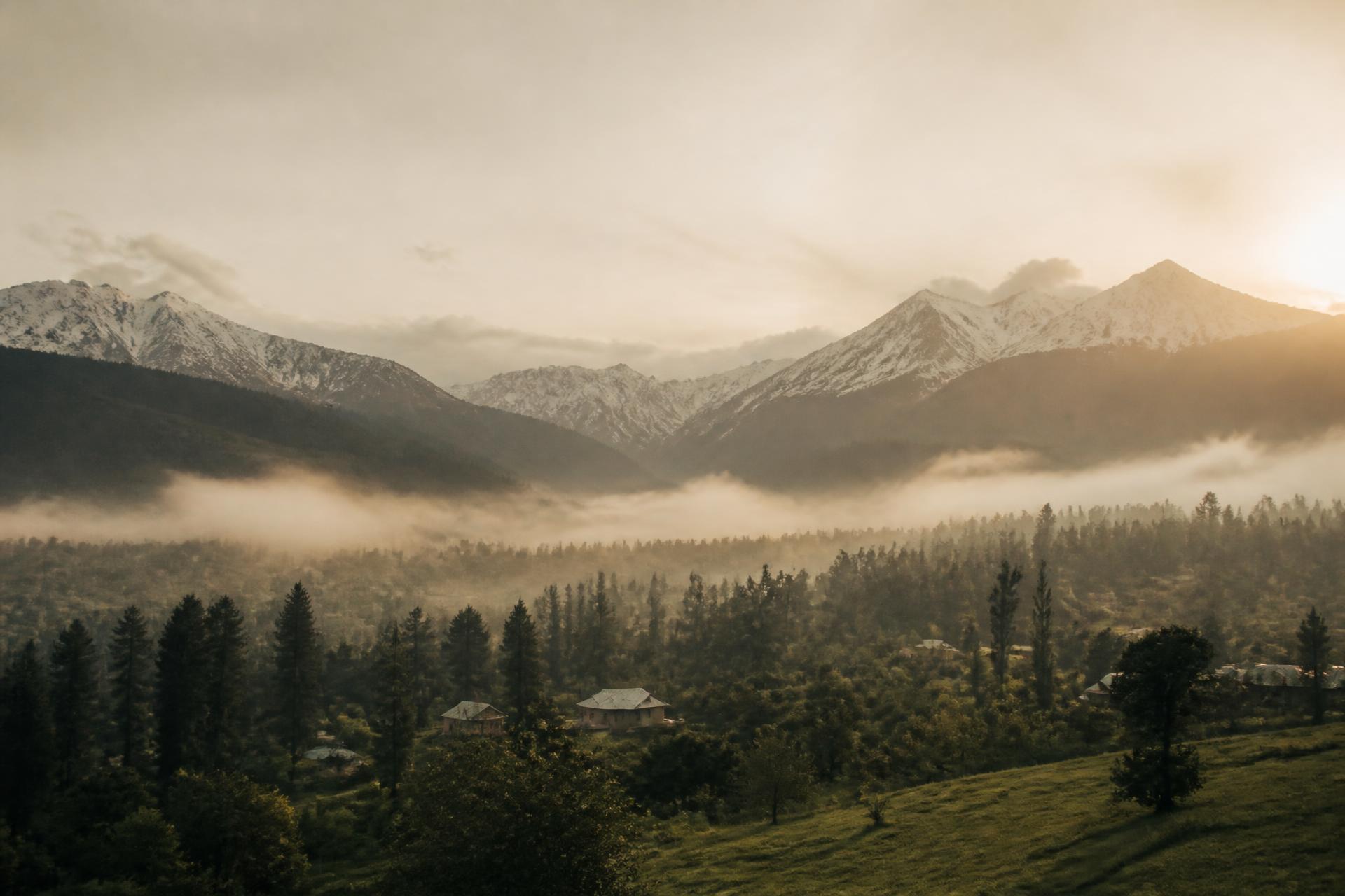 Misty Kashmir valley at dawn with snow-capped mountains